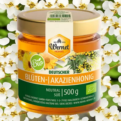 Honig Wernet Bio deutscher Blüten- und Akazienhonig 500 g im Glas, goldfarbener Honig vor Blütenhintergrund, neutral süß, mit Bio-Siegel und Originaletikett