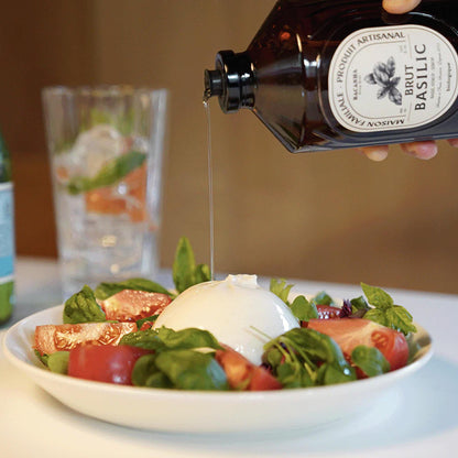 Bacanha Bio-Basilikum-Sirup wird als raffiniertes Dressing über einen frischen Tomate-Mozzarella-Salat (Burrata) mit Basilikumblättern gegossen.