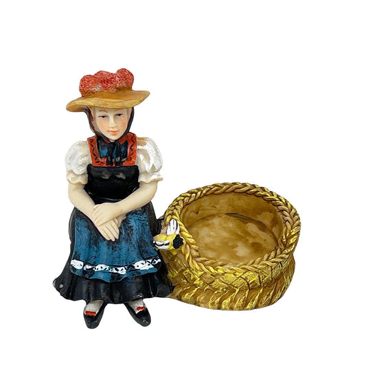 Vogelperspektive einer Schwarzwälder Deko-Figur – Handbemalte Miniatur einer Frau in Tracht mit Bollenhut neben einem offenen, geflochtenen Bienenkorb.