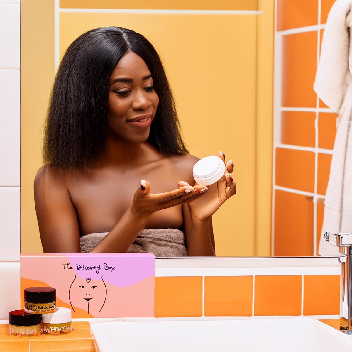 Eine lächelnde Frau im Badezimmer betrachtet einen Pflegebalsam aus der Baûbo „The Discovery Box“ – Ein Bio-Geschenkset für natürliche Körperpflege, präsentiert am Waschbecken.