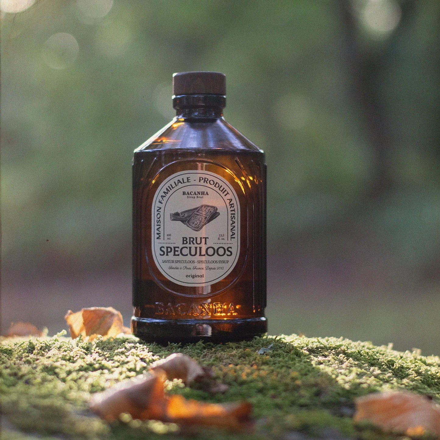Bacanha Sirop Brut de Speculoos Bio – französischer Bio-Spekulatius-Sirup in Glasflasche auf moosigem Waldboden im natürlichen Licht
