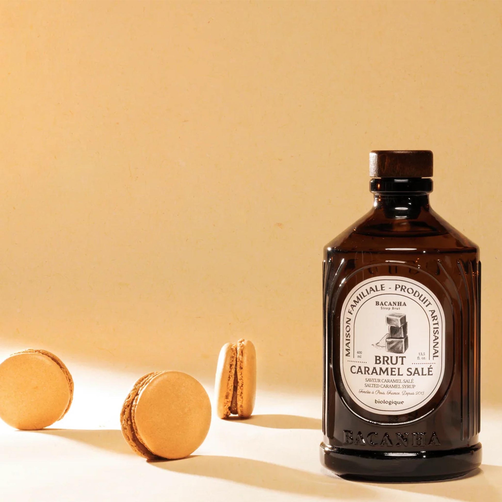 Bacanha Sirop Brut de Caramel Salé Bio – französischer Bio-Sirup mit gesalzenem Karamell aus Bio-Rohrzucker, stilvoll arrangiert mit Karamell-Macarons