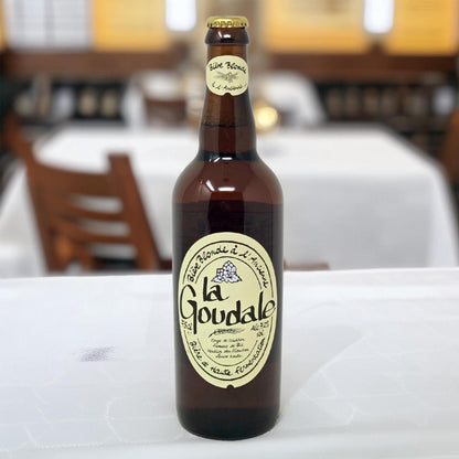 Eine Flasche La Goudale Bière Blonde à l’Ancienne auf einem weiß gedeckten Tisch – französisches Starkbier in der 0,75-Liter-Flasche für gehobenen Genuss.