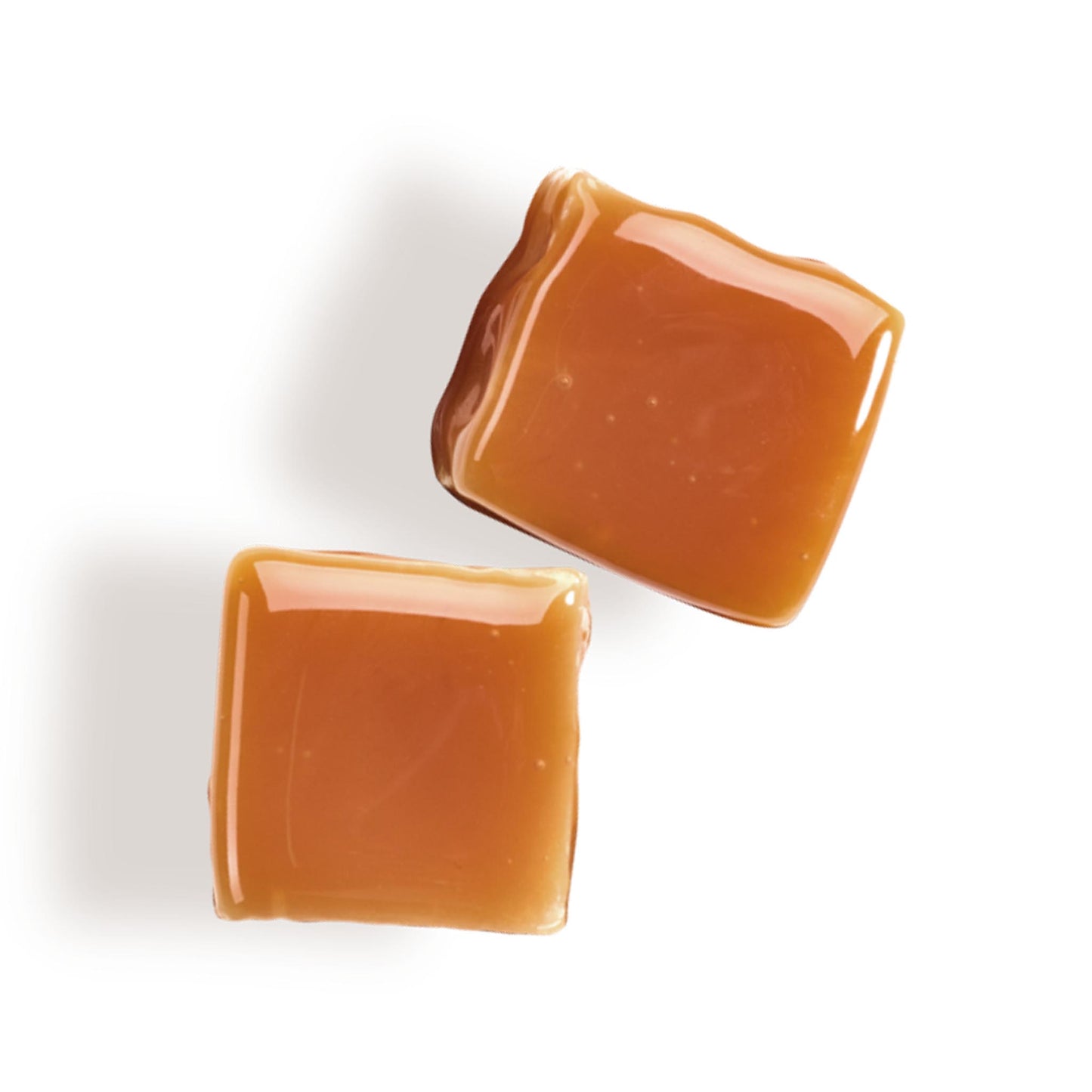 Zwei weiche, glänzende Karamell-Bonbons (Karamellwürfel) in der Draufsicht auf weißem Hintergrund.